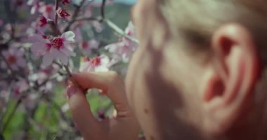 Bahar çiçeklerini açan doğal ormanın tadını çıkaran bir kız. Kadın yüzü, el ele tutuşan çiçekler. Etkileyici bir seyahat. Tenerife Santiago del Teide.