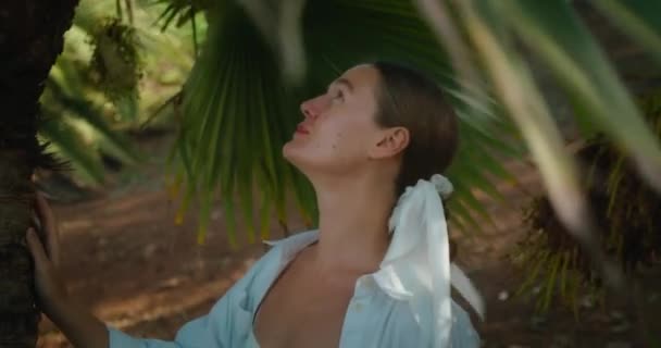 旅行妇女喜欢在热带花园丛林里与棕榈树散步 女孩的近视脸在绿色的棕榈枝之间 慢动作 引人注目的旅行 — 图库视频影像