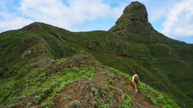 Roque yolu Taborno. Yeşil dağların üzerinden insansız hava aracı uçuşu. Turist kadın yürüyüş, patika. Doğa manzarası. Yalnız seyahat. Tenerife Kanarya Adası İspanya. Mirador Fuente del Lomo.