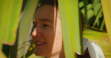 Tropik yeşil palmiye yapraklı kız. Doğal kadın güzelliği. Gün batımı ışığı ve gölgeler yüz yüze. Seyahat deneyimi