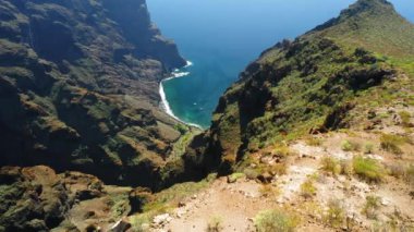 Tenerife dağlarının hava görüntüsü. Yeşil tepeler, uçurumlar, kayalar, çıkıntılar, ekilmemiş doğa manzarası. Tepelerdeki bahar çimenleri. Masca köyü ve körfez. Kanyonun muhteşem manzarası. Kanarya Adası. Kimse..