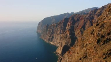 Uçuşlar uçurumlar, derin mavi okyanuslar, büyük uçurumlar Acantilados de Los Gigantes, Tenerife, İspanya. Beyaz sis. Huzur. Birkaç yelkenli. Issız kayalık volkanik dağlar. Kimse..