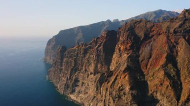 Suyun üzerindeki muhteşem manzara, güzel kahverengi ve kırmızı renkli kayalar. Dalgalar kayalıklara çarpıyor. Okyanusun ortasındaki Tenerife Adası. Dünyayı dolaş. Canlı mavi renkler. Kimse..