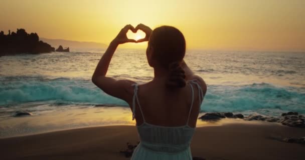 Dziewczyna Plaży Zachodzie Słońca Pokazuje Symbol Serca Dłońmi Letnie Wakacje — Wideo stockowe