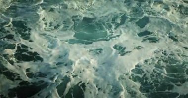 Fırtınada okyanus dalgaları köpüklü su arka planı. Tepesinden aşşağıya inen deniz yüzeyi yavaş çekimde yakın çekim. Su kristal gibi berrak. Fırtınalı hava.