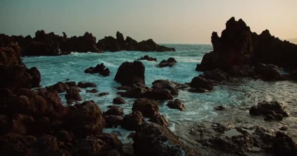 汹涌的海浪划过汹涌大海中央的黑色火山岩 热带岩石海岸附近发泡水的惊人景象 — 图库视频影像