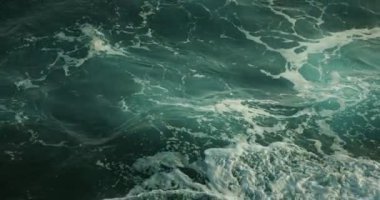 Güçlü fırtınalı deniz dalgaları olan berrak okyanus suyu. Turkuazın üstü tamamen köpüklü. Dünya elementi. Yakın çekim ağır çekim sinematik deniz manzarası.