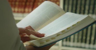 Kadın kütüphanede kitap okumayı kendi kendine öğrendi. Kadın eli, açık bir kağıdın sayfasında parmak uçlarında gezdiriyor. Eğitim kavramını öğreniyorum. Ağır çekimde yakın çekim.