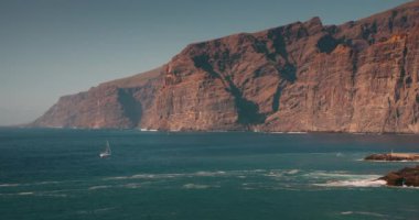 Tenerife, Kanarya Adaları 'ndaki Acantilados de Los Gigantes sahilindeki kayalıklar ve okyanus manzarası. Yavaş çekim deniz dalgaları, güneşli bir günde kayalık kıyılara çarpar..