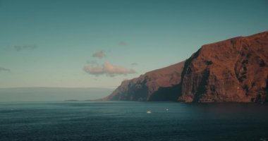 Tenerife Kanarya Adası 'nda devasa dağ kayaları olan sakin okyanus manzarası. Yaz tatili manzarası. Tenerife Kanarya Adaları İspanya Avrupa. Los Gigantes uçurumları.