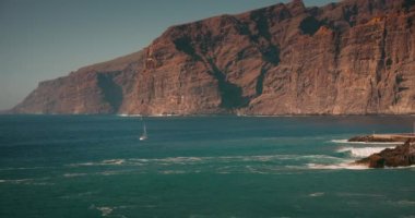 Tenerife, Kanarya Adaları 'ndaki Acantilados de Los Gigantes sahilindeki kayalıklar ve okyanus manzarası. Yavaş çekim deniz dalgaları, güneşli bir günde kayalık kıyılara çarpar..