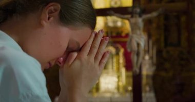 Kadın kilisede Tanrı 'ya dua ederken başını eğdi. Kurtarıcı İsa 'ya dua etmek için katlanmış eller. Hıristiyanlık dini kavram. Yakın çekim sinematik görünüm.