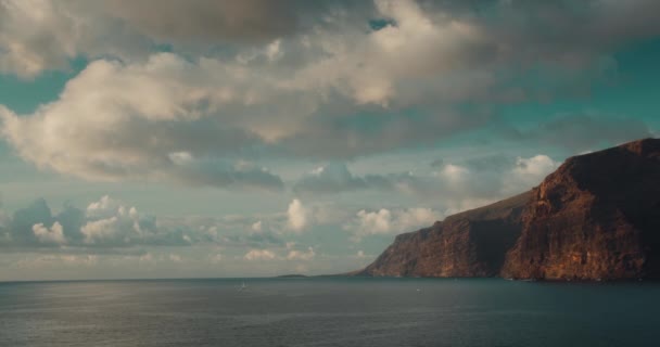 金光闪闪的时候 落基海景映衬着多云的蓝天 在西班牙 欧洲特内里费加那利群岛海岸黑色火山岩附近平静的海水 Los Gigantes悬崖 — 图库视频影像