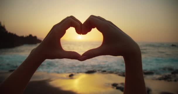 일몰에 손으로 상징을 보여주는 해변에 여행자 손가락 사이의 Seascape 슬로우 — 비디오