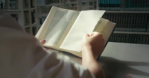 Człowiek Czytający Książki Bibliotece Ręce Trzymają Biblię Otwartą Drewniane Półki — Wideo stockowe