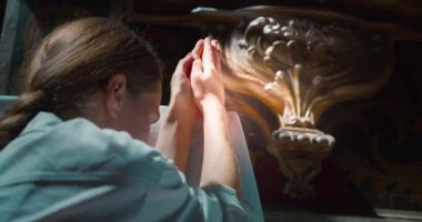 Kilisenin karanlık bir köşesinde Tanrı 'ya dua eden bir kadın. Kurtarıcı İsa 'ya dua etmek için katlanmış eller. Hıristiyanlık dini kavram.