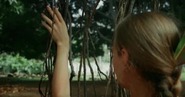 Kadın elinin tropik bir ağacın köklerini okşaması. Doğayla bütünlük kavramı.