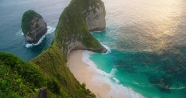 Nusa Penida Endonezya 'daki Kelingking plajına yağmur yağıyor. Sahilde yeşil kayalıkları olan inanılmaz okyanus manzarası. Ağır çekimde 4k 'lık yüksek kaliteli görüntüler..