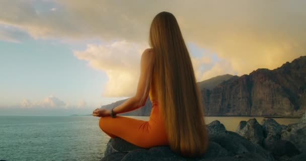 Frau Praktiziert Yoga Und Meditiert Lotusposition Felsigen Strand Des Ozeans — Stockvideo