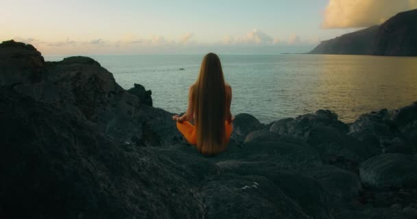 Mulher Pratica Ioga Medita Posição Lótus Praia Rochosa Oceano Visão — Vídeo de Stock
