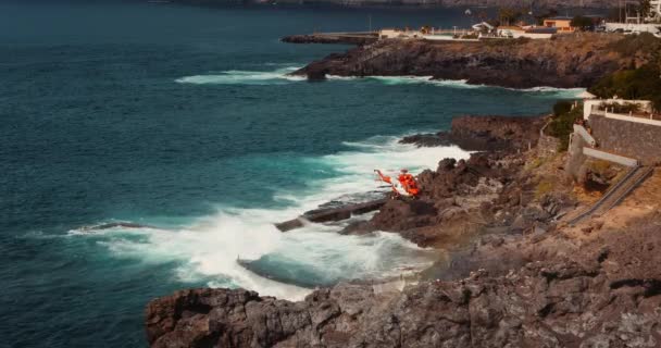 医疗直升机降落在岩石火山海岸进行救援行动 航空为伤员提供急救 暴风雨般的海滩 Tenerife加那利群岛西班牙欧洲Los Gigantes悬崖 — 图库视频影像