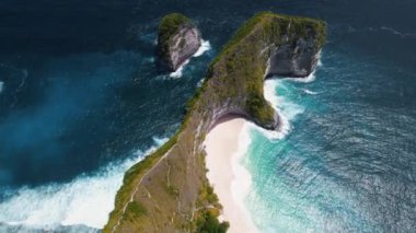 Bali 'deki Nusa Penida Kelingking plajının havadan görüntüsü. T-Rex dinozoru şeklinde bir kaya. Asya Endonezya 'da ünlü bir yerin üzerinde uçuyor. Yeşil uçurumları ve derin mavi okyanus dalgaları olan renkli bir park..