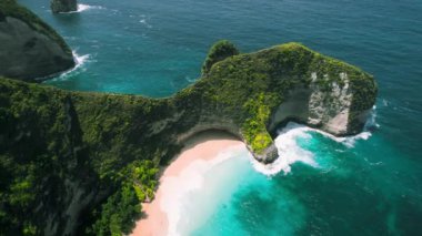 Bali 'deki Nusa Penida Kelingking plajının havadan görüntüsü. T-Rex dinozoru şeklinde bir kaya. Asya Endonezya 'da ünlü bir yerin üzerinde uçuyor. Yeşil uçurumları ve derin mavi okyanus dalgaları olan renkli bir park..