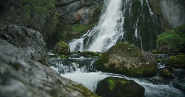 山の川が斜面を流れている 透明な水泡と緑のモスでオーバーグラウンドのボールダーにスプラッシュ ザルツブルクのゴリンジャー ワッサーフォール — ストック動画