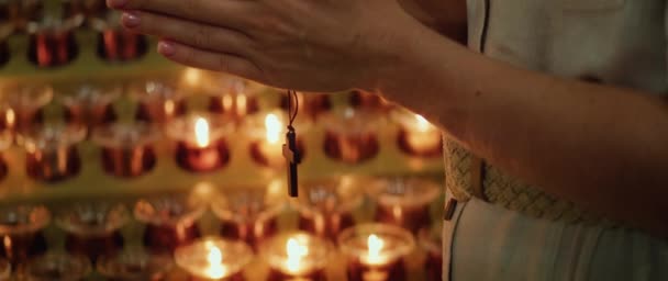 在耶和华殿中 女性的手拿着木制的宗教十字架 靠近点燃着炽热的蜡烛 基督徒对上帝的信仰 — 图库视频影像