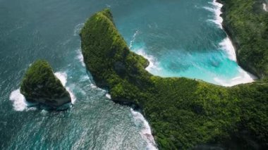 Kayalık okyanus kıyısındaki dağ yağmur ormanları. Açık deniz dalgaları, Bali Endonezya 'daki Nusa Penida egzotik adasını yıkar. Kelingking plajı. Meşhur turistik mekan, mutlaka ziyaret edilmeli. Hava aracı bakış açısı.