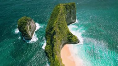 Nusa Penida Bali Endonezya 'da altın kumlu sahil Kelingking' i olan kayalık okyanus kıyısı. Açık deniz dalgaları egzotik adaları yıkar. Meşhur turistik mekan, mutlaka ziyaret edilmeli. Hava aracı bakış açısı.