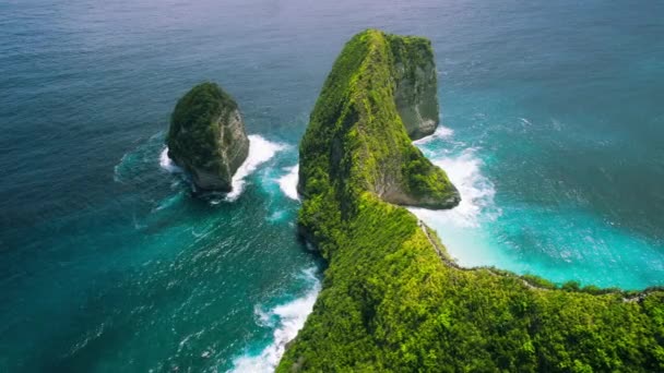 海岸に面した緑豊かな熱帯林で 美しい砂浜とアジアの海の波が楽しめます ヌサペニダ バリのケリングビーチ アジア インドネシアの有名な場所の上空を飛ぶ カラフルなジュラシックパーク — ストック動画