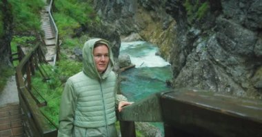 Yağmurlu bir günde dağ nehri boyunca yürüyüş yapan bir kadın. Avusturya 'daki kanyon boyunca dar ahşap merdiven. Bulutlu doğanın tadını çıkaran kız. Lammerklamm vadisi..