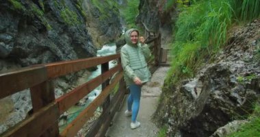 Kamera nehir boyunca dağlarda seyahat eden bir kadını takip ediyor. Mutlu kız elini sallıyor ve onu takip etmeni istiyor. Yağmurlu havada kayalık bir vadide yürüyüş yapan bir turist. Dar tahta merdiven içeri