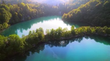 Gün doğumunda gölde sakin su bulunan dağlık yaprak döken orman. Yazın manzaradan güneşli sabahta sonbaharın başına kadar. Plitvice Lakes Ulusal Parkı Hırvatistan.