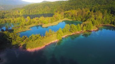 Dağ gölünün en saf ayna suyu ve sık yeşil orman manzarası yaz ayından sonbahar güneşli sabahına kadar. Doğal havuzların berrak turkuaz suyu. Plitvice Gölleri Ulusal Parkı