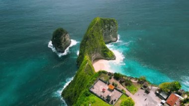 Bali 'deki tropik kayalık sahil şeridi. Turistler tehlikeli bir dağ yolu boyunca kumlu Kelingking plajına inerler. En ikonik simge ve popüler turistik eğlence tapınağı dağın tepesinde.