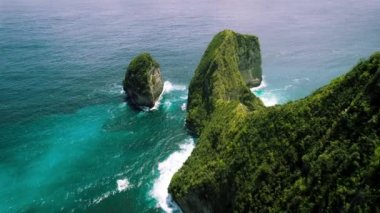 Kayalık okyanus kıyısındaki dağ yağmur ormanları. Açık deniz dalgaları, Bali Endonezya 'daki Nusa Penida egzotik adasını yıkar. Kelingking plajı. Meşhur turistik mekan, mutlaka ziyaret edilmeli. Hava aracı bakış açısı.