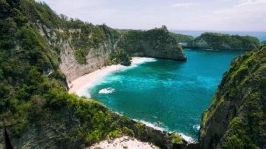 Bali 'deki Diamond Plajı' nda bir dağ kayalığı. Saf okyanus dalgaları altın kumda yuvarlanıyor. Nusa Penida tropikal adasının havadan görünüşü.