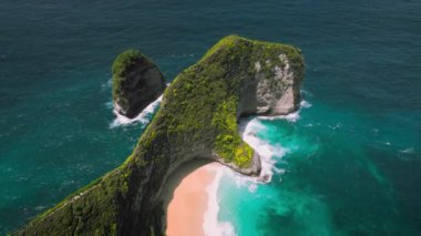 Bali 'deki Nusa Penida Kelingking plajının havadan görüntüsü. T-Rex dinozoru şeklinde bir kaya. Asya Endonezya 'da ünlü bir yerin üzerinde uçuyor. Yeşil uçurumları ve derin mavi okyanus dalgaları olan renkli bir park..