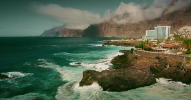 Güçlü deniz dalgaları, Tenerife Kanarya Adaları 'nda doğal yüzme havuzu olan fırtınalı okyanusa çarpar. Charco de Isla Cangrejo. Ağır çekimde kayalıklara su köpüğü sıçrıyor. Puerto Santiago