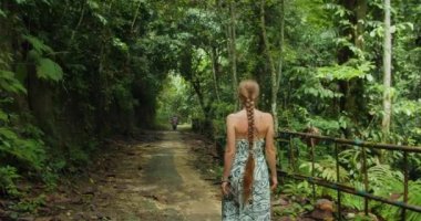 Bali, Nusa Penida, Endonezya 'daki Tembeling plajı ve ormanı yakınlarında ormanda yürüyen bir kadın turist. Yazın tropik doğa manzarası