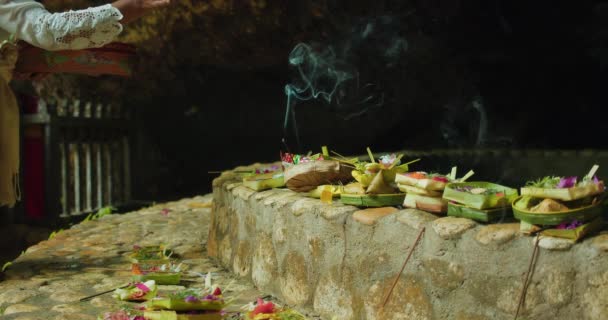 バリの女性はヒンドゥー教の神に捧げ物の儀式を行います 燃える香りが屋外に散りばめられています バリヌサペニダのインドネシア文化 アロマ香の煙 — ストック動画