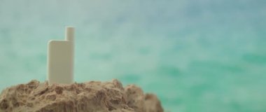 Kadın eli, kayalık sahilde köpüklü okyanus suyuyla kaplı bir kavanoz kozmetik ürünü çıkarıyor. Tatilde güneş kremi, hidrasyon ve cilt bakımı kavramı. Bulanık göl ile uzayı kopyala.
