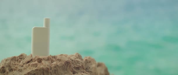 雌性手在有闪亮海水背景的岩石海滩上摘下一罐化妆品 度假时的防晒 护肤等概念 有模糊湖泊的复制空间 — 图库视频影像