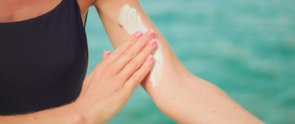 女性手部的特写用Spf乳霜涂在覆盖着摩尔的皮肤上 在有海水背景的海滩上 女孩在肩上涂防晒霜 — 图库视频影像