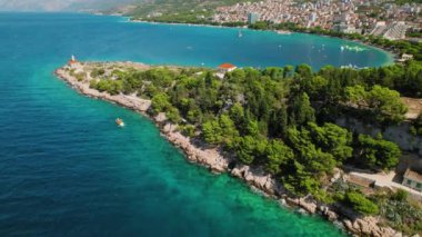 Yeşillik ve Gök Denizi ile Makarska Rivieras Sahili. Dalmaçya kıyısı boyunca yoğun yeşilliklerle çevrili deniz fenerinin havadan görünüşü..