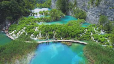 Gölün berrak zümrüt suyu üzerindeki ahşap dar köprünün inanılmaz manzarası. Manzaralı şelalelerle dağ ulusal parkında yürüyüş yapmak. Plitvice Lakes Ulusal Parkı Hırvatistan. Seyahat ve doğa