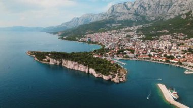 Makarska Rivieras Virstine Plajları ve Urban Vista in Summer Bliss. Hırvatistan 'ın berrak sularına sahip hareketli bir sahil kasabasının hava manzarası..