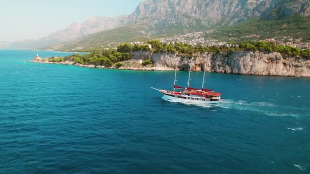 壮观的海岸景观 一艘红色的帆船在岩石悬崖边巡航 在克罗地亚的夏季海景 热门旅游胜地 — 图库视频影像